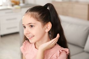 A girl shows off the hearing aid on her ear.