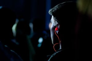 A man wears earplugs at a concert. 