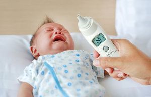 A baby and a thermometer showing a fever.